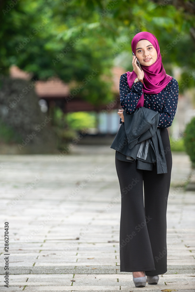 Muslim Businesswoman Talking on her smartphone at a park. Negative Space for text. Muslim Businesswoman Talking on her smartphone at a park. Negative Space for text.