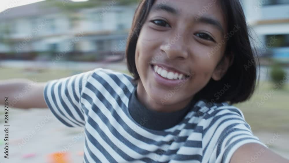 Asian girl little is playing a carousel at the park. Asia girl kid Wearing a black and white striped shirt Asian girl little is playing a carousel at the park. Asia girl kid Wearing a black and white striped shirt