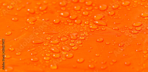Raindrops on a tent of orange color as an abstract background