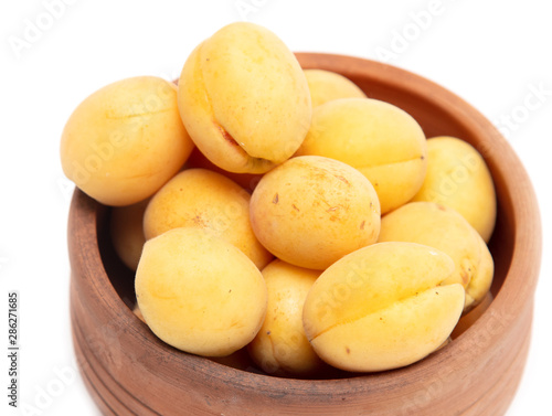 Ripe apricot in clay pot on a white background
