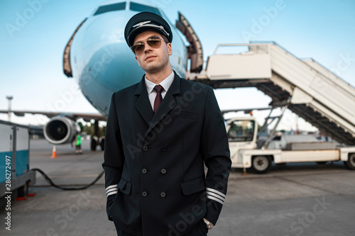 Serious male pilot in uniform waiting for flight in airport