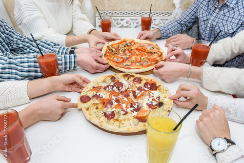 Friends eat pizza and drink juice in cafe. Close up © RomanR