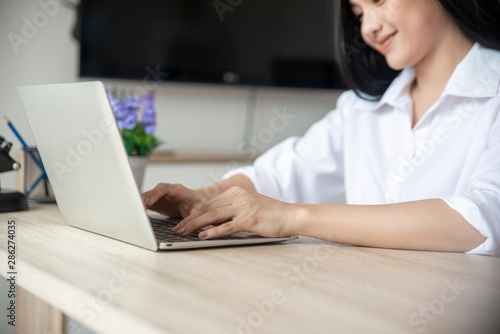 Asian Student typing report and research in library.Business woman working on laptop.Beautiful young freelancer writing blog and internet work online at home office.Student and technology concept