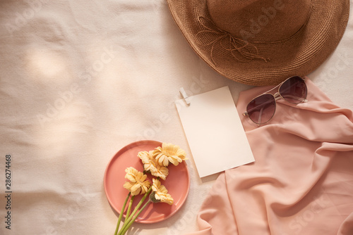 Flowers on the plate with hat, galsses and card on the light background photo