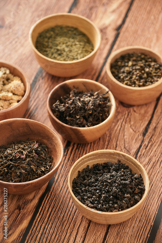 assortment of dry tea in white bowls on wooden surface