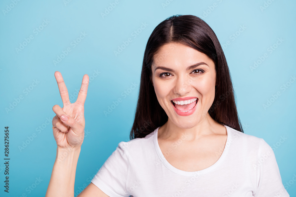 Photo of laughing nice cute fascinating attractive girlfriend showing you v-sign while isolated with blue background Photo of laughing nice cute fascinating attractive girlfriend showing you v-sign while isolated with blue background
