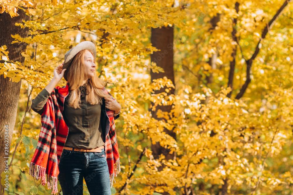 Portrait of a young blonde in the autumn forest, a girl in a gray hat. A woman wears a warm checkered scarf. Solar lighting. place for text. Portrait of a young blonde in the autumn forest, a girl in a gray hat. A woman wears a warm checkered scarf. Solar lighting. place for text.