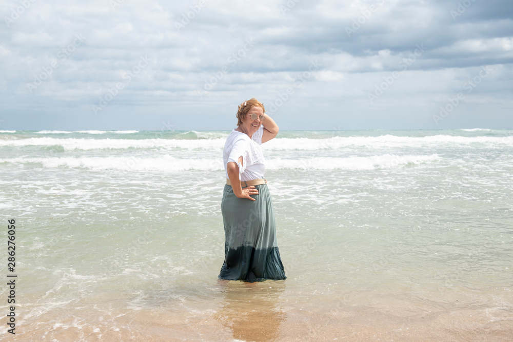 Beautiful mature woman posing on the beach Beautiful mature woman posing on the beach