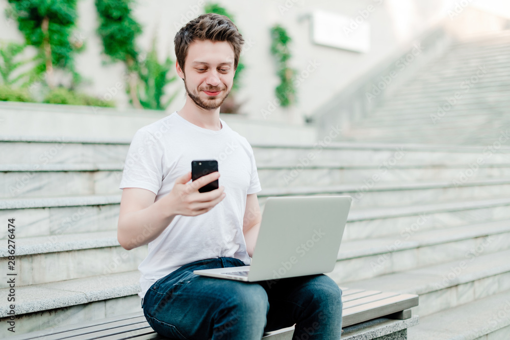 man using phone and laptop for freelance work outdoors man using phone and laptop for freelance work outdoors
