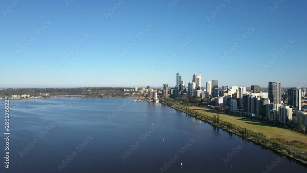 Beautiful scenic aerial view of drone flight above Swan River along the skyline of Perth, capital of Western Australia, with summer sunny blue sky and horizon as background. Beautiful scenic aerial view of drone flight above Swan River along the skyline of Perth, capital of Western Australia, with summer sunny blue sky and horizon as background.