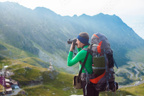 man with backpack on the mountain. photographer taking photos