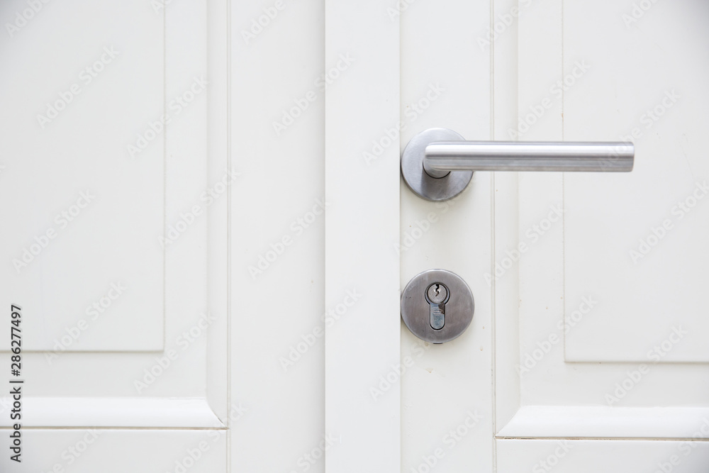 Silver aluminium modern metal handle on a white wooden door Silver aluminium modern metal handle on a white wooden door