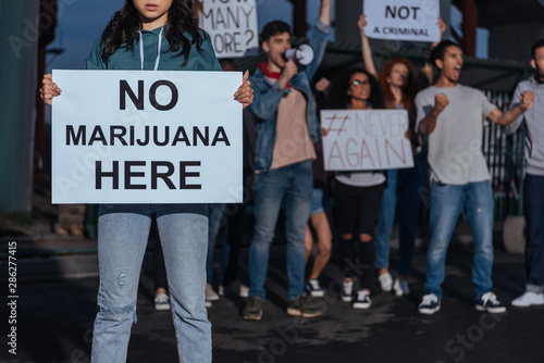 cropped view of woman holding placard with no marijuana lettering near screaming multicultural people © LIGHTFIELD STUDIOS