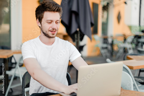 man using laptop for remote work in cafe