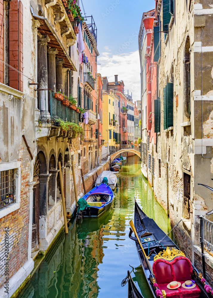 Venice, Veneto, Italy July 24 2017 a view down a tributary canal with gondola and boats moored along side houses
