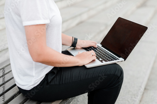 woman typing on laptop keyboard on the street
