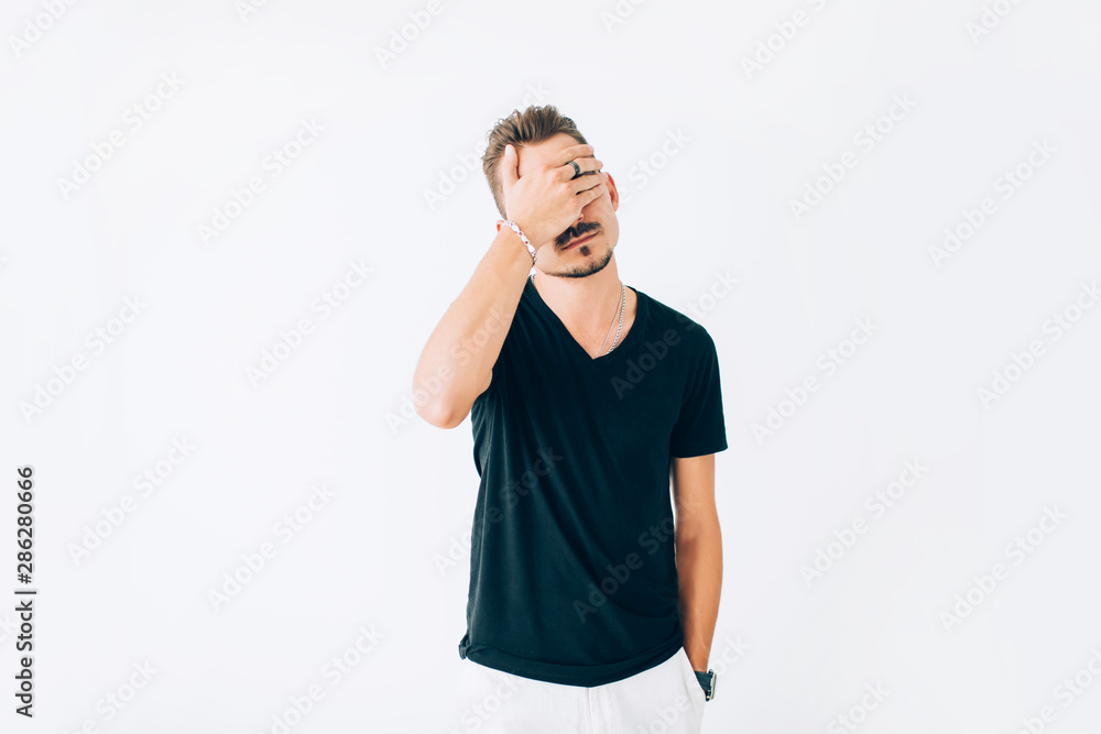 Disappointed young man covering his face with a palm on white isolated background. Disappointed young man covering his face with a palm on white isolated background.