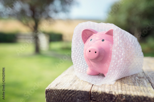 Fotografie Piggy bank wrapped in bubble wrap, protecting your money