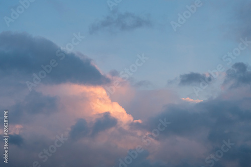 Background with white, gray and black coulds against blue sky at sunset time.