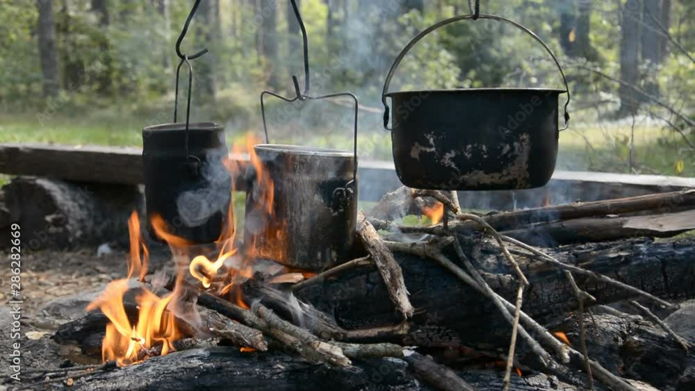 Camping fire in the evening with a pot heated on it, hd stock footage Camping fire in the evening with a pot heated on it, hd stock footage