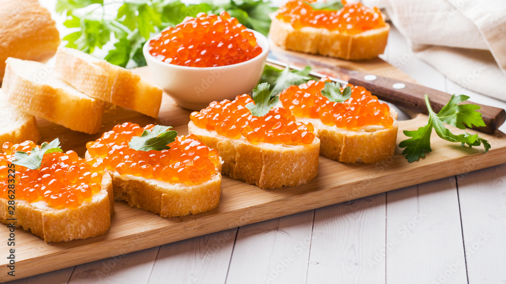 Sandwiches with red salmon caviar on a wooden Board. White table top. Sandwiches with red salmon caviar on a wooden Board. White table top.