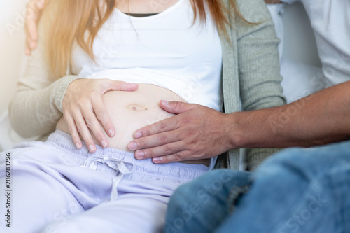 Pregnant woman in bed with man. Asian woman with white man. Mix race relationship concept.