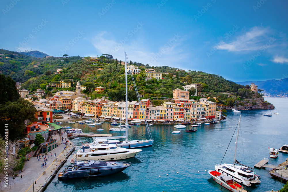 Fototapeta premium Beautiful small village Portofino with colorfull houses, luxury boats and yachts in little bay harbor. Liguria, Italy. On warm brigth summer day