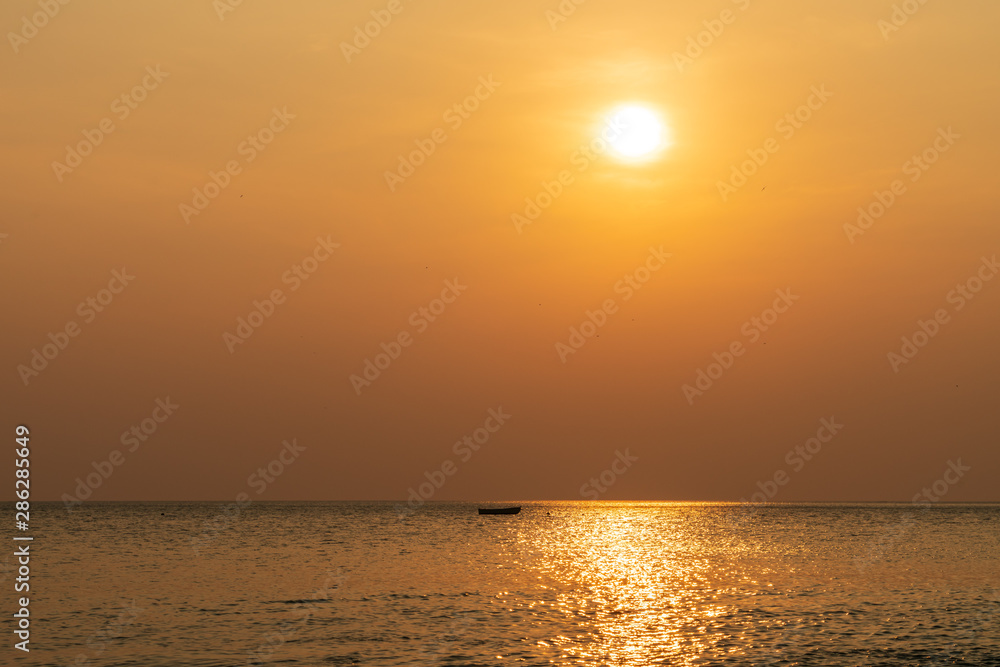 Sunset in Costa Rica along pacific coast with single small boat on the ocean surface