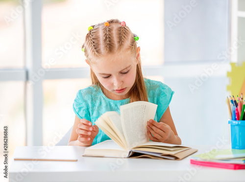 Cute kid girl lovely reading at the table