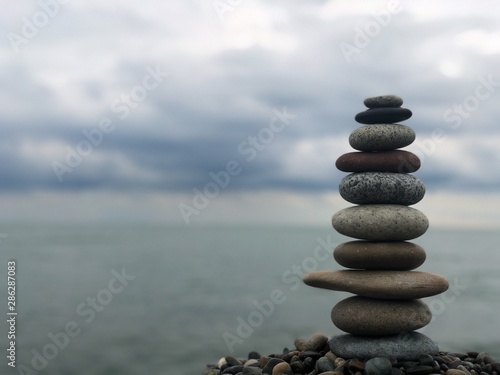 Marine theme  stones on the shore. The stones are stacked in a pyramid against the background of the sea. Pyramid of small stones on the beach. The concept of harmony of balance and meditation. 