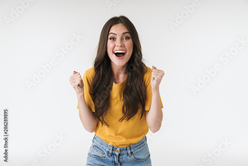 Image of astonished brunette woman wearing casual t-shirt screaming and rejoicing
