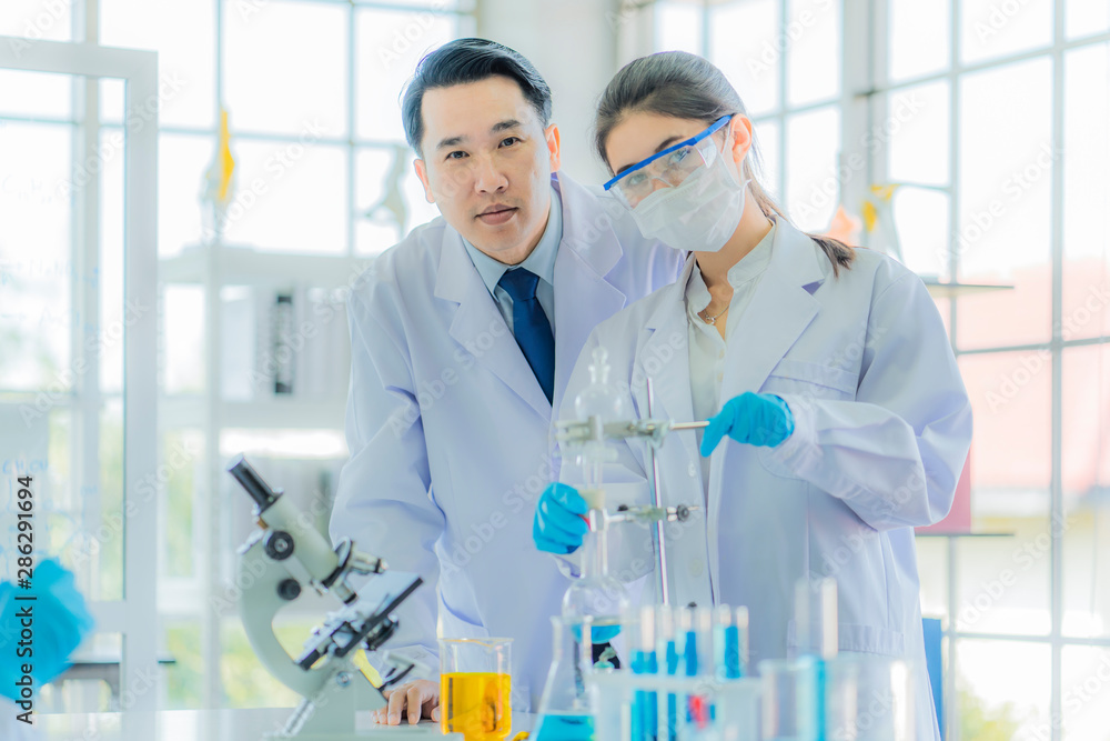 A handsome asian professor proud to teaching biology and chemist for young beautiful girl scientist. Beauty scientist use alcohol lantern for experiment in laboratory at morning university classroom. A handsome asian professor proud to teaching biology and chemist for young beautiful girl scientist. Beauty scientist use alcohol lantern for experiment in laboratory at morning university classroom.