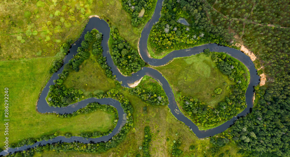 Top view drone shot of a green field, forest and river Top view drone shot of a green field, forest and river