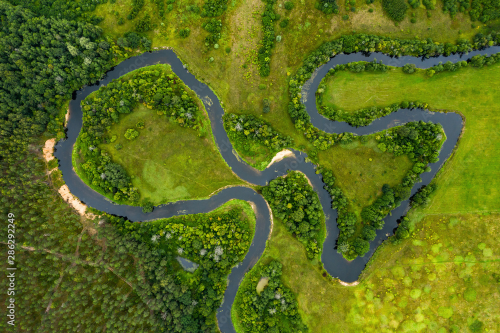 Top view drone shot of a green field, forest and river Top view drone shot of a green field, forest and river