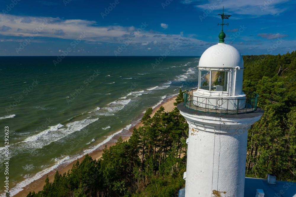 Top view of the sea and the Uzhava lighthouse. Blue sky. Green forest. Top view of the sea and the Uzhava lighthouse. Blue sky. Green forest.