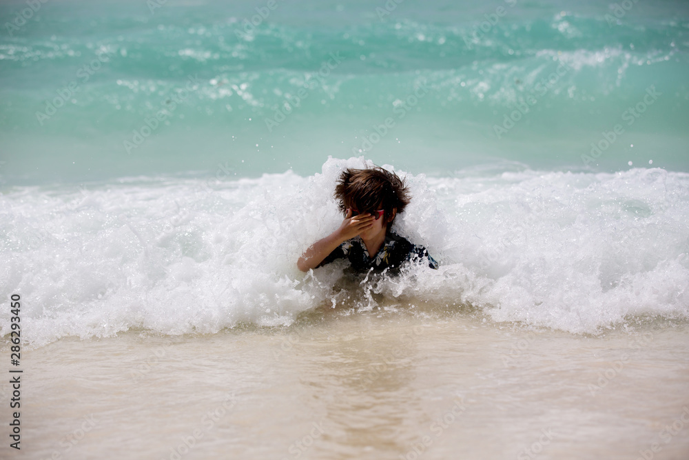 Adorable preschool children, boys, having fun on ocean beach. Excited children playing with waves, swimming, splashing happily Adorable preschool children, boys, having fun on ocean beach. Excited children playing with waves, swimming, splashing happily