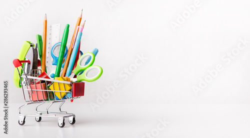 Shopping cart with office stationery isolated on white photo