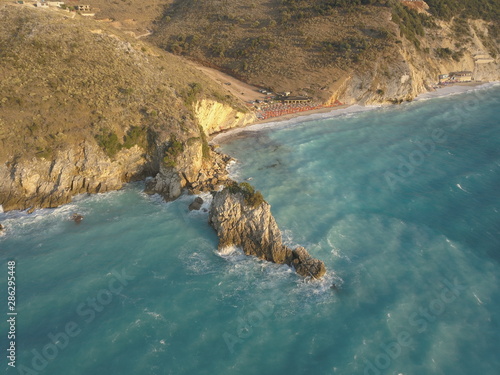 Aerial view of small beach with turquoise water next to rocks and trees in the area of Agia Paraskevi Halkidiki, Greece. View from drone photo