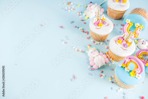 Cute unicorn and rainbow cupcakes, light blue background, copy space
