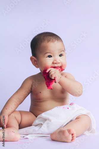 asian cute baby girl eating red dragon fruit. newborn baby on white background