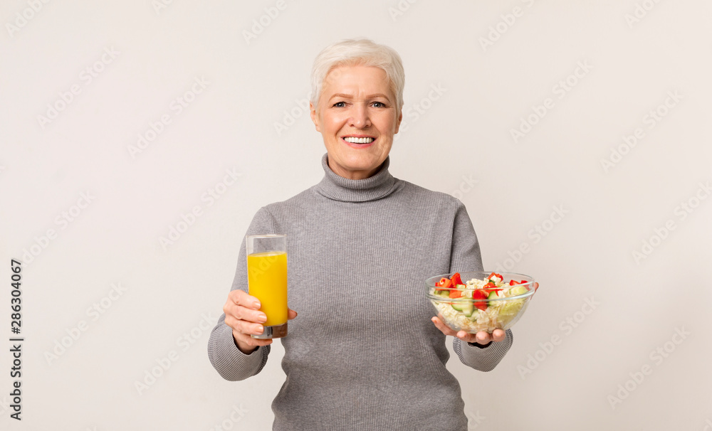 Beautiful aged lady dining with fresh vegetable salad and juice Beautiful aged lady dining with fresh vegetable salad and juice
