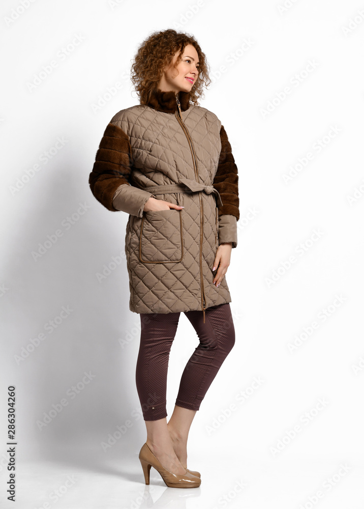 Curly girl poses demonstrating beige quilted zipping mini coat combined with fur sleeves and fur mandarin collar Curly girl poses demonstrating beige quilted zipping mini coat combined with fur sleeves and fur mandarin collar