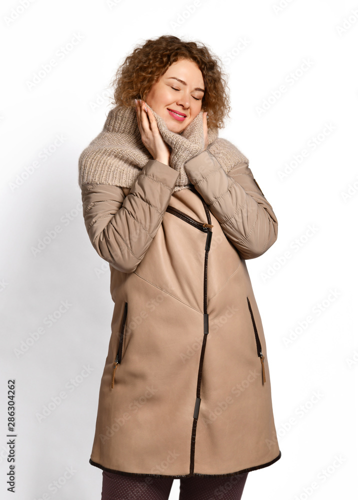 Tall woman in modern stylish beige sheepskin coat combined with textile sleeves and knitted scarf enjoying the warmth Tall woman in modern stylish beige sheepskin coat combined with textile sleeves and knitted scarf enjoying the warmth