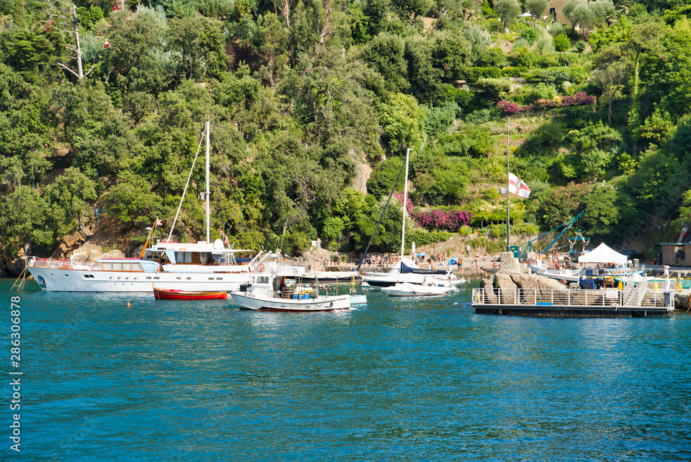 Portofino, Italy - AUGUST 15, 2019: Portofino harbor with yachts and nature of the Ligurian coast / popular European resort / ideal vacation