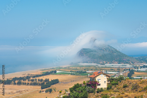 Beautiful landscape with rare atmospheric effect when fog looks like climbing over hill. photo