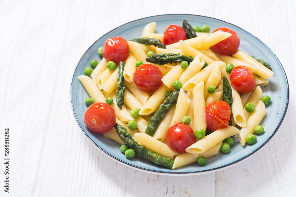 Penne pasta salad with asparagus , tomatoes and peas