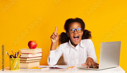 Happy First-Grade Student Girl Pointing Finger Up Sitting At Laptop