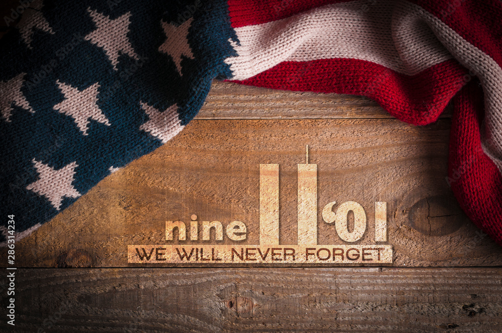 A scarf with the colors of the American flag on a wooden table and an inscription in memory of September 11th. Patriot day 2019. - obrazy, fototapety, plakaty 