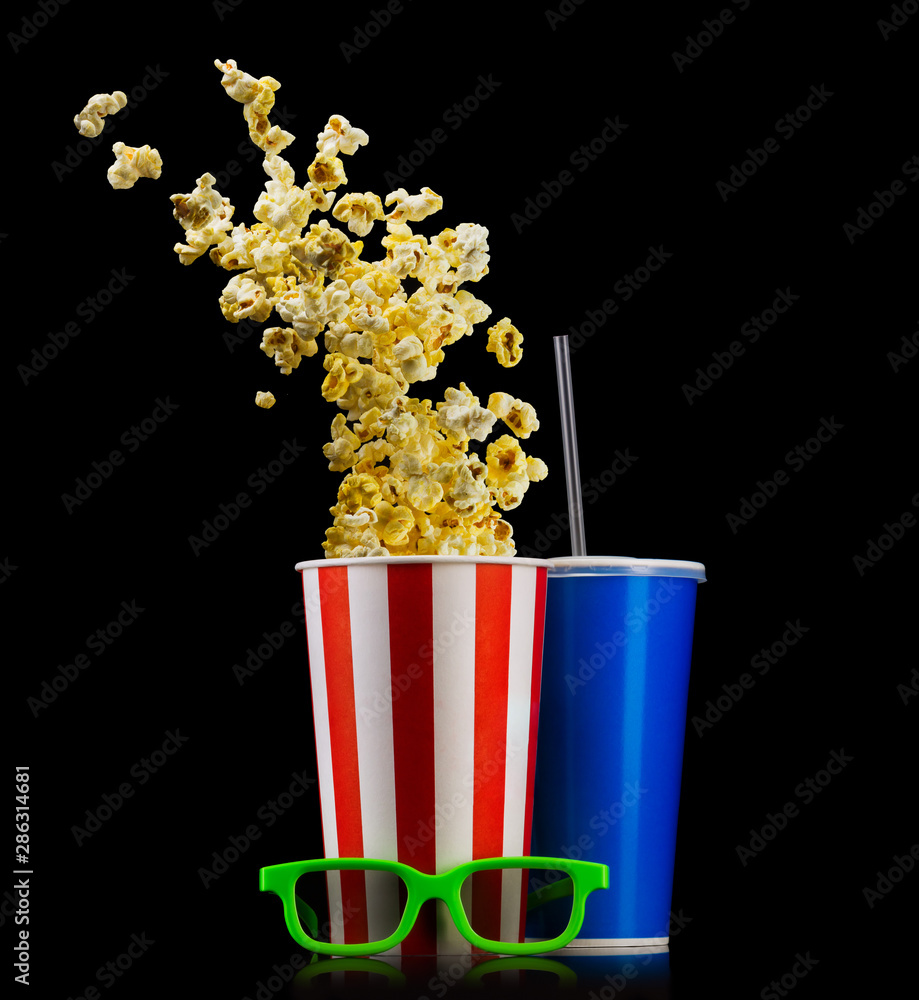 Paper striped bucket with popcorn, cup of drink and glasses isolated on black