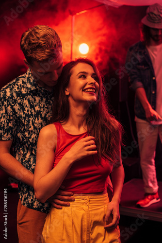 man and smiling young woman during rave party in nightclub